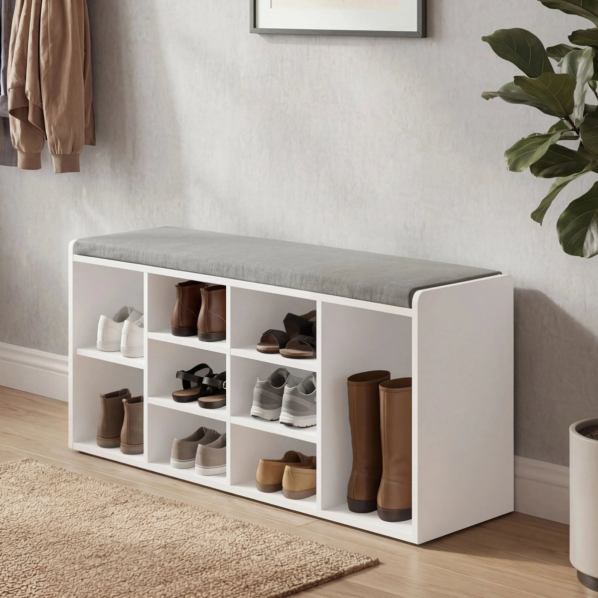 [White] shoe storage bench with shoes in a room with a plant and framed picture.