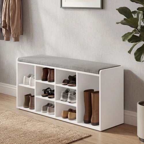 [White] shoe storage bench with shoes in a room with a plant and framed picture.
